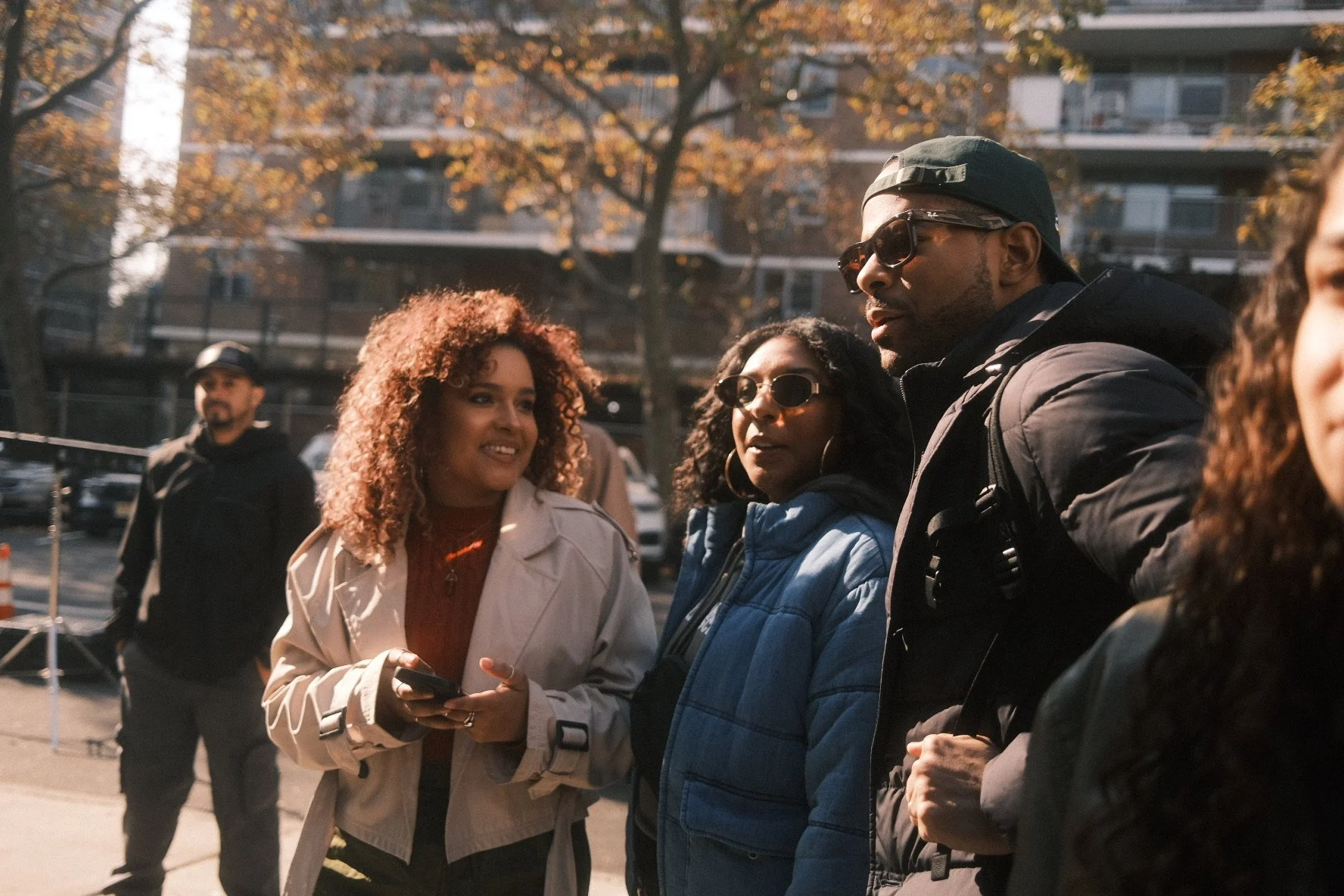 Group of diverse young adults standing outdoors, having a conversation on a sunny day
